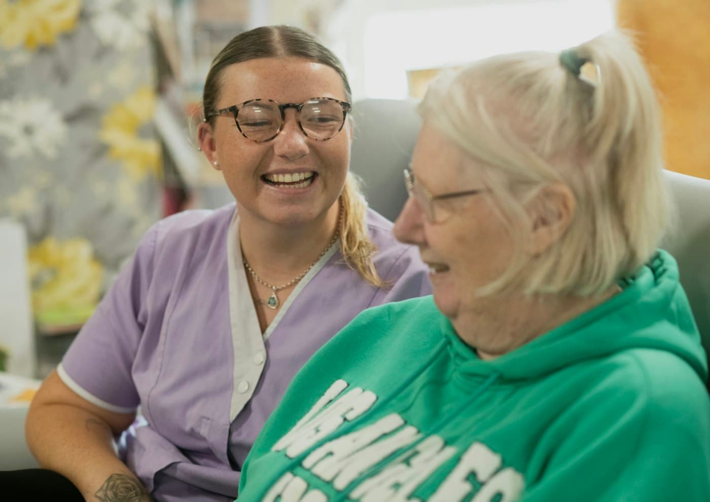 A smiling carer sharing a laugh with an older woman